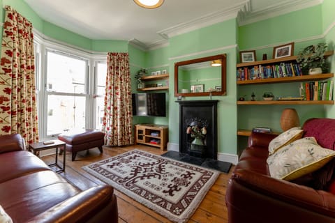 The living room features comfortable sofas, books, and a TV for relaxing evenings