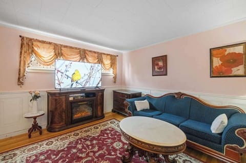 Inviting living room with cozy seating, electric fireplace, and smart TV—blending Victorian charm with modern comfort.