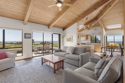 Sink into the sofa and take in sweeping ocean views through floor-to-ceiling glass, where the vaulted wood ceiling and natural light set the tone for your Sea Ranch escape.