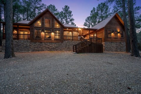 Stunning log cabin nestled among towering trees, featuring warm lighting and a welcoming stone foundation in a peaceful forest setting.