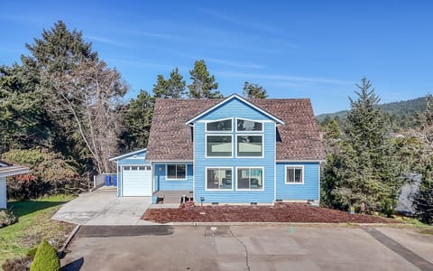 Charming blue vacation home nestled among towering evergreens with mountain views and spacious parking for your getaway.