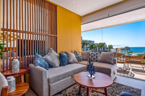 Relax in a beautifully designed living space featuring comfortable seating, modern décor, and a private balcony with refreshing ocean views.