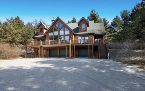 Torch Lake estate exterior with wooded surroundings and paved driveway.