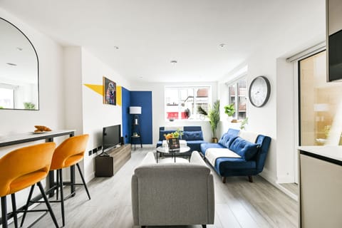 Bright open-plan living room with two sofa beds, a TV and the breakfast bar at one end
