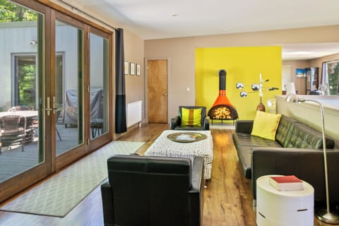 Modern mid-century lounge on the main level featuring a decorative vintage stove and designer seating. This bright social hub opens directly to the 33ft deck, offering a seamless indoor-outdoor connection to the Acadia National Park border.