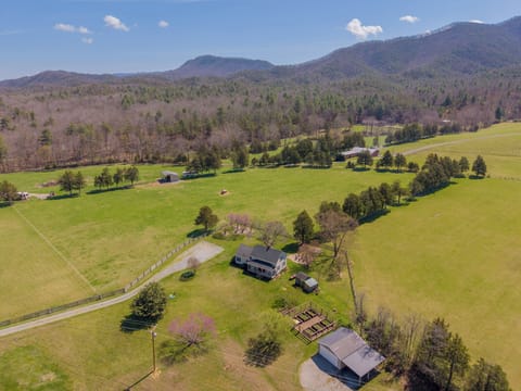 A scenic farmhouse nestled within expansive, fenced pastures and surrounded by rolling mountain vistas.