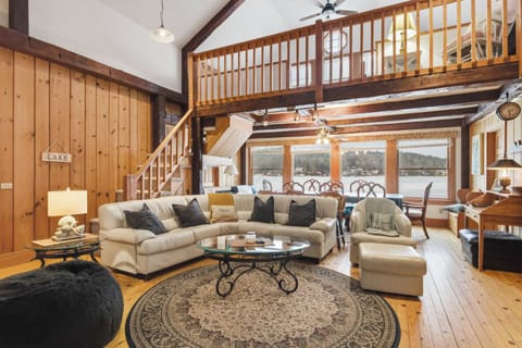 Cathedral ceilings, exposed timber beams, and knotty pine walls set the tone the moment you walk in — the lake fills the windows straight ahead.