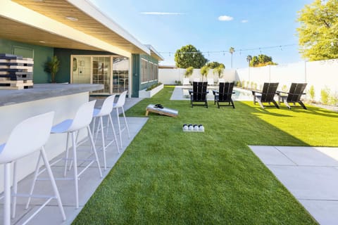 Beautiful backyard oasis featuring a heated pool, yard games, luxe chaise pool lounge chairs, and outdoor firepit!