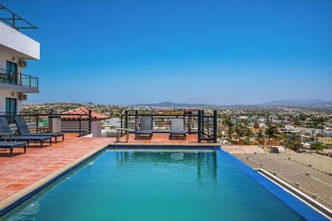 Shared rooftop pool w/ loungers & open sky views, perfect for a refreshing dip