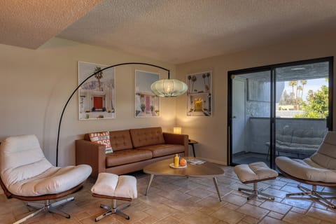 Unwind in your stylish living room with comfortable leather seating and modern amenities, featuring a peaceful balcony view.