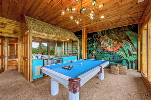 Lazy Bear's game room with large windows offering a scenic mountain views and access to a balcony with rocking chairs