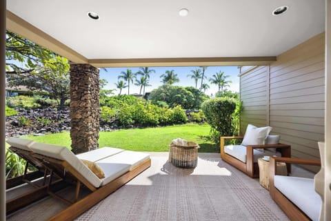 Natural Acacia wood loungers and oversized armchairs anchor this private primary lanai, set at ground level with garden outlook and seamless indoor-outdoor living.
