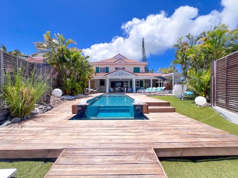 Exterior view of the pool with a glass wall and the wooden deck at Villa Belle Bleue in Saint-François.
