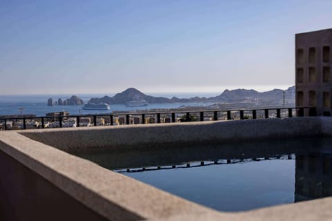 Elevated pool terrace w/ water views & mountain silhouettes in the distance