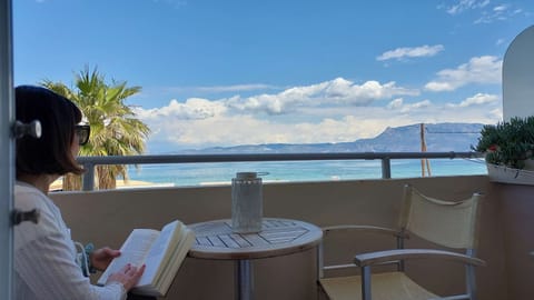The balcony table and chairs with the Gulf of Corinth spread out directly in front — this is where most mornings will start and most evenings will end, with a view that earns the studio its place on the waterfront.
