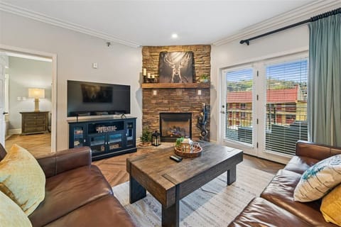Cozy up by your stone fireplace while enjoying mountain views through French doors in this stylish living space.