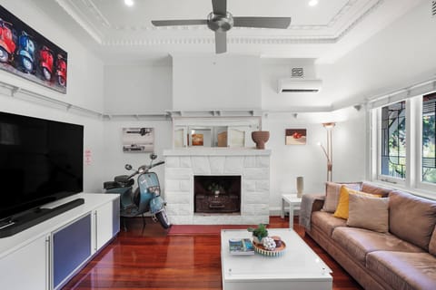  Bright and airy living space featuring a display fireplace, split AC/heating, ceiling fan, and high ceilings