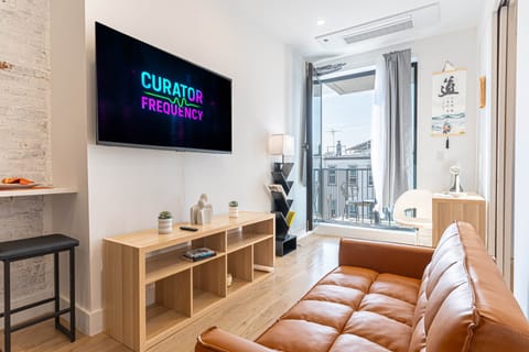 Bright living area with sofa, TV, workspace, and balcony access