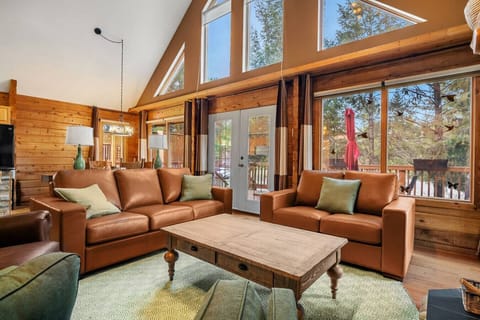 Main floor living room with a wood-burning fireplace, board games, cozy seating options and walkout access to the deck.