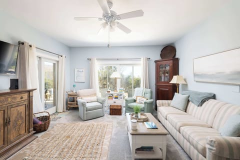 Living area with comfortable seating, wall-mounted TV, and plenty of natural light from sliding glass doors ceiling fan, and direct access to the outdoor patio