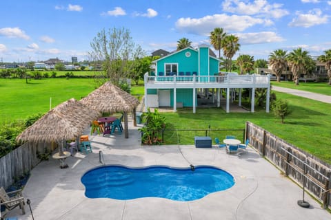 Spacious vacation home with private fenced in-ground pool, large yard, elevated beach house design, and covered outdoor entertainment area.