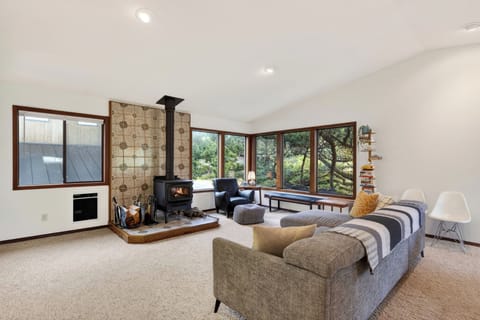 Spacious living area featuring a wood-burning stove with decorative tile and large windows.
