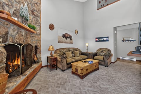 Cozy up by your crackling stone fireplace in this rustic living room, where comfortable seating and mountain charm create the perfect retreat.