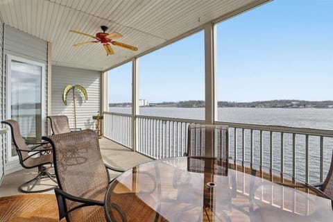 Covered lakefront balcony with dining, fan, and sweeping views