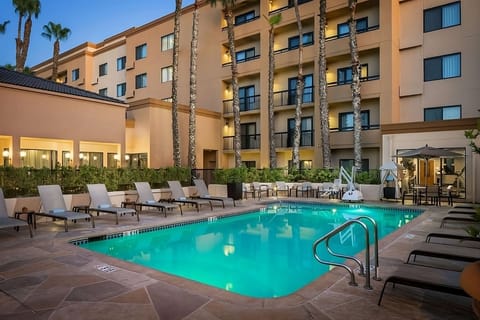 Unwind by the glowing pool with loungers at dusk.