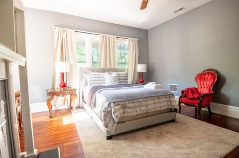 The modern bed frame is paired with charming traditional-style accent furniture, creating a cozy, inviting space with a quiet retreat feel.