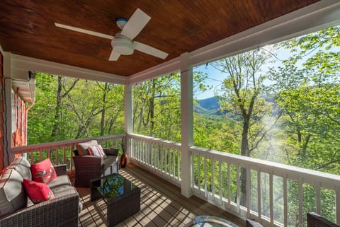 Screened porch with a ceiling fan and partial mountain views.