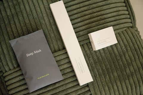  Bedroom amenities laid out on the bed, including sleep mask, earplugs, toothbrush for guest comfort and convenience.