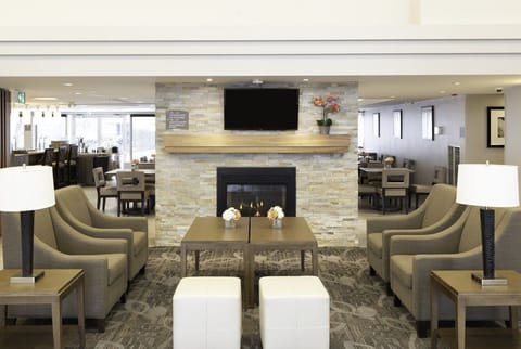 Stone-surround fireplace with armchairs and soft lighting in the Great Room — social hour happens here Monday through Wednesday.