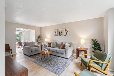 Living Room | Unit 1 | Main Floor
Shared living space with a sofa, an armchair, and coffee table. Side tables available for personal items. Open layout with direct access to the dining area and kitchen. Located on the main floor near the front entry.