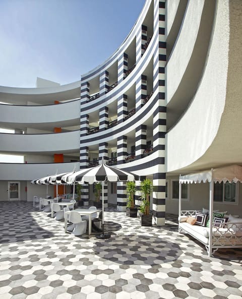 Sip coffee under striped umbrellas in the sunlit courtyard.