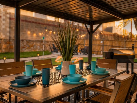 Covered outdoor dining for 8 with the putting green and firepit in back