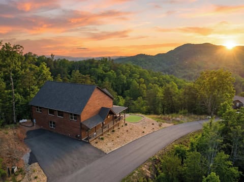 Cabin exterior surrounded by mountain scenery & glowing sunset skies