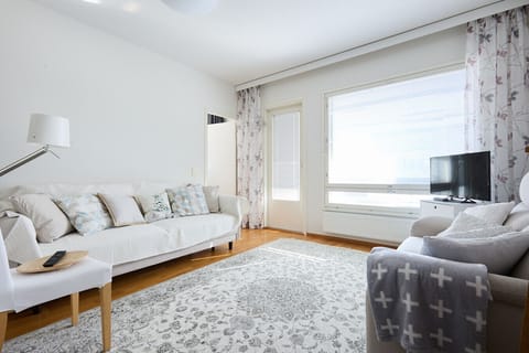 Relax in a bright, sun-drenched living area designed for comfort, featuring a large sofa and a flat-screen TV for your entertainment. The open layout provides a seamless flow between the lounge and the dining areas.