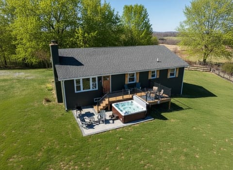 Aerial view of Green Apple Farm`s private cabin, featuring a spacious deck with a hot tub and scenic pastoral surroundings.