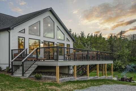 Luxury countryside retreat featuring a private basketball court, hot tub, expansive wraparound deck, and outdoor fire pit, surrounded by peaceful wooded views.