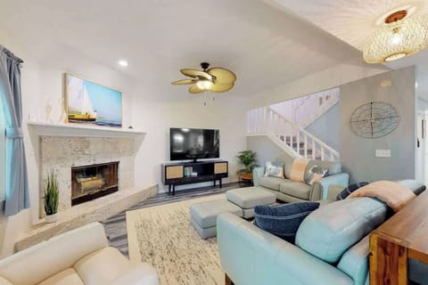 Relax in this bright living room featuring a stone fireplace and coastal-inspired decor.