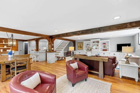 Bright open concept living room with custom built ins, warm wood floors, and a dramatic brick hearth in this Eastham vacation rental.
