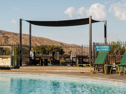 Dive into sunny pool time with shaded loungers nearby.