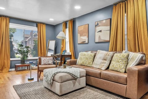 Bright living room w/ warm golden curtains, cozy sofa, & rug — made for relaxing evenings in.
