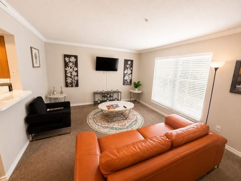 Bright, cozy living room with leather sofa, TV, and large sunny window