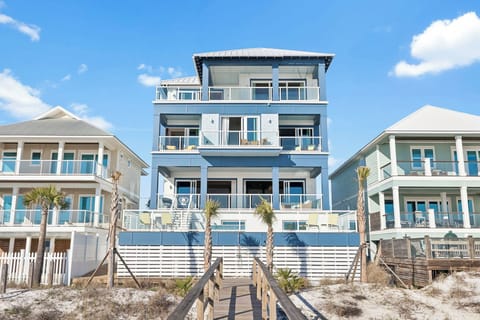 Modern beachfront property with multiple decks and direct beach access via wooden walkway.