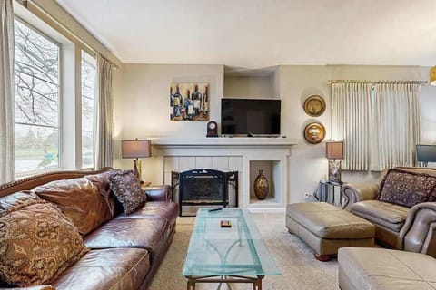 Sink into plush leather seating by the gas fireplace after a day exploring Sonoma vineyards — your living room features a flat-screen TV and warm, curated decor throughout.