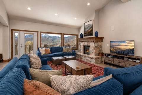 Sink into plush blue sofas and gaze at stunning mountain vistas through expansive windows. A cozy fireplace, warm wood accents, and vibrant rugs create your perfect mountain retreat.