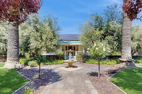 Stroll through your manicured courtyard garden with a stone fountain, flowering olive trees, and palm-framed pathways—a true Healdsburg farmhouse welcome.