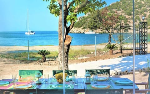 Large outdoor dining area set directly in front of the bay, offering uninterrupted sea views. Positioned under natural shade, it’s ideal for long meals outdoors from morning coffee to sunset dinners.